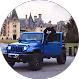 Blue Jeep Wrangler parked on grass with historic castle buildings in the background.